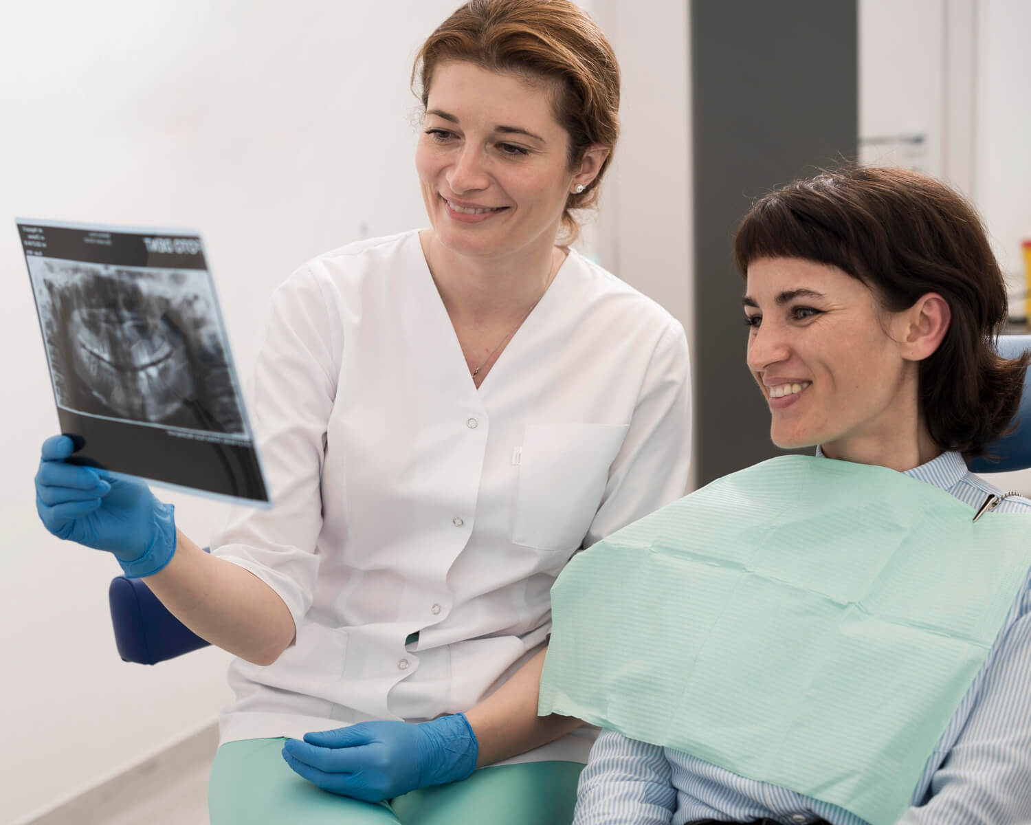 Dentista na Illuminer em São Bento do Sul mostra tomografia de implante para paciente sorridente em consulta de avaliação segura.